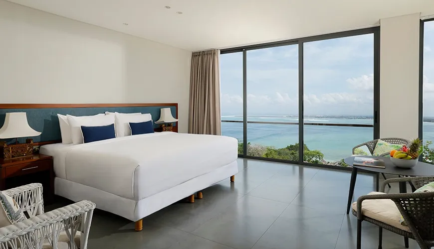 Bright master bedroom featuring a large bed and two chairs with an incredible ocean view at Villa Santos Cliff View