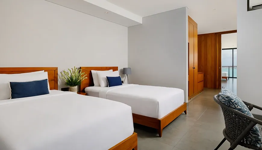 Comfortable twin bedroom featuring two beds with clean white linens and stylish wooden furniture at Villa Santos Cliff View