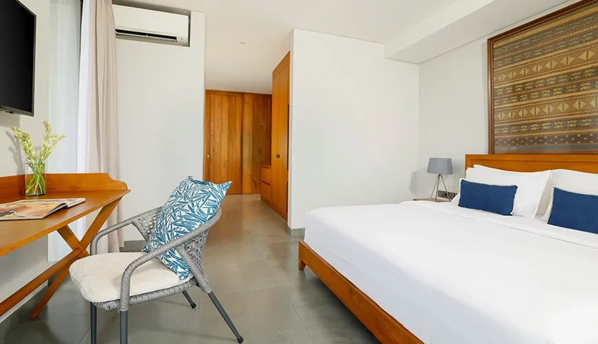 Stylish bedroom featuring a wooden bed, a writing desk, and intricate textile art on the wall at Villa Santos Cliff View