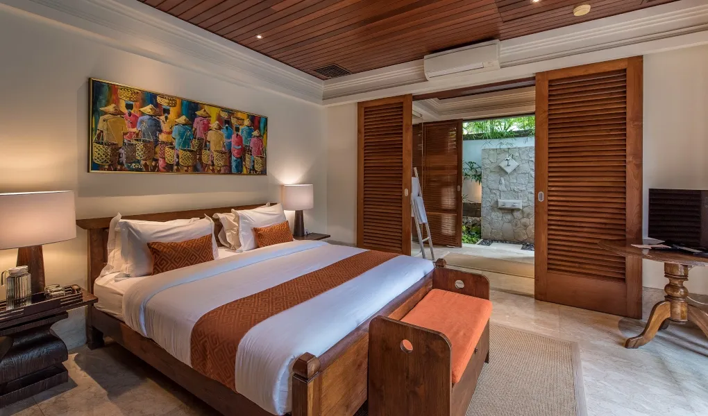 Balinese guest room with artwork and outdoor shower access at Villa Senada