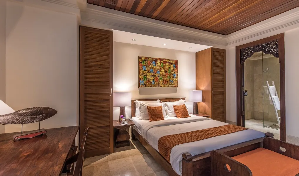 Balinese guest room with rich wood tones and artwork at Villa Senada