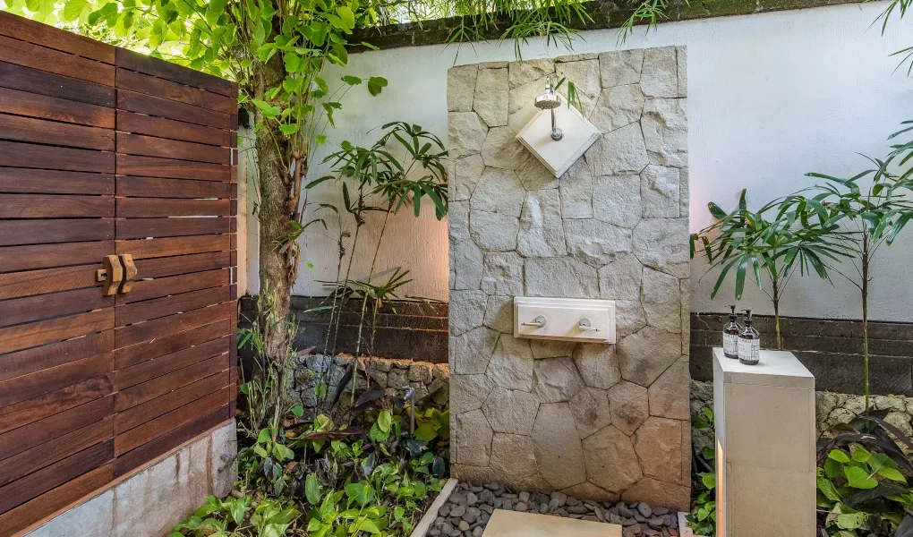 Private outdoor stone shower surrounded by lush greenery at Villa Senada