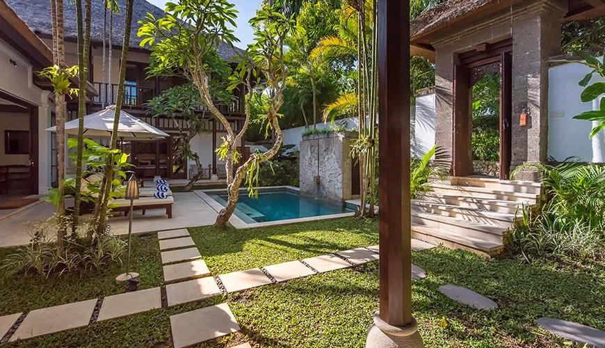 Serene plunge pool surrounded by lush garden and traditional structures at Villa Senada
