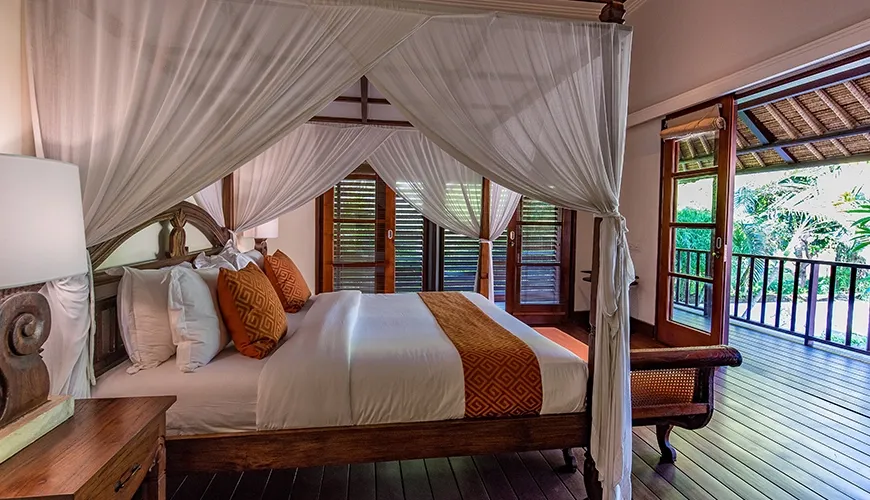 Spacious master bedroom with canopy bed and private balcony access at Villa Senada