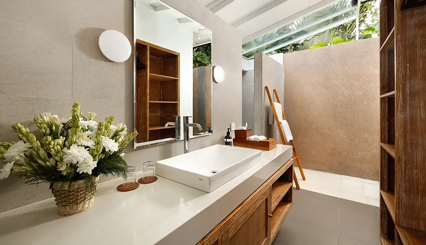 Bright and modern villa bathroom with a clean white sink, large mirror, and open-air shower area at Villa Swarna