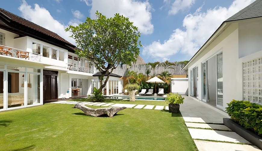 Lush green villa garden with pool and stepping stone path at Villa Swarna