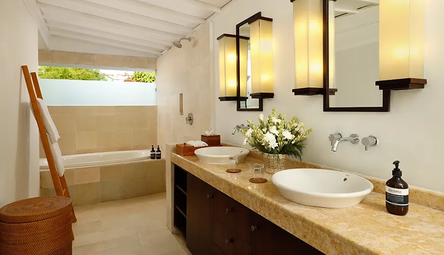 Luxurious villa bathroom featuring a double vanity with stone countertops, a large bathtub, and warm lighting at Villa Swarna