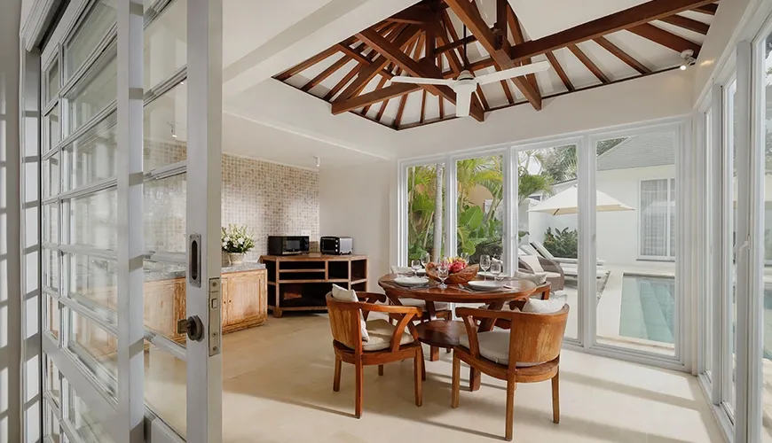 Round wooden dining table glass doors pool view at Villa Swarna