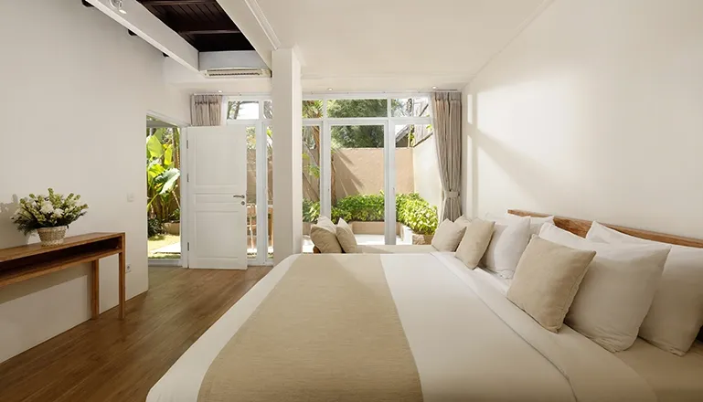 Spacious bedroom king bed open to lush tropical garden view at Villa Swarna