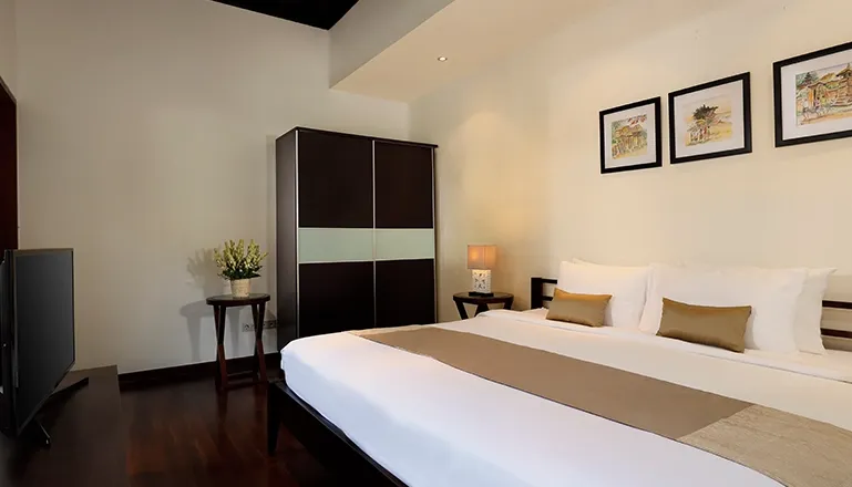 Modern bedroom king bed wardrobe TV framed art at Villa Tenang