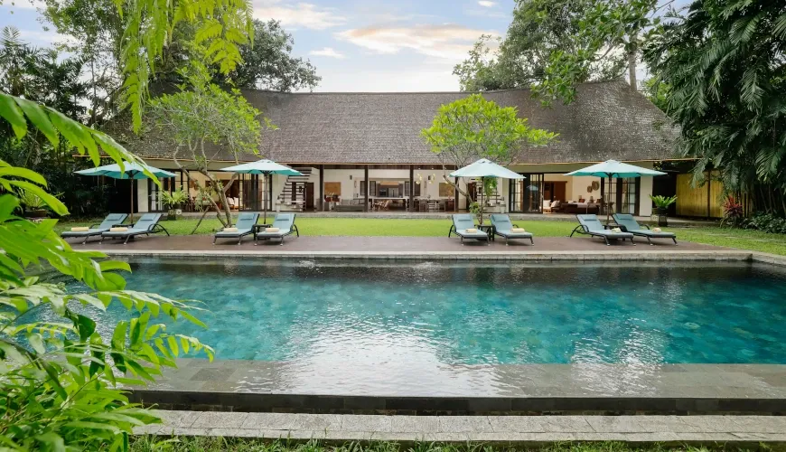 Large villa with a long rectangular pool and several sun loungers at Villa Tirtadari