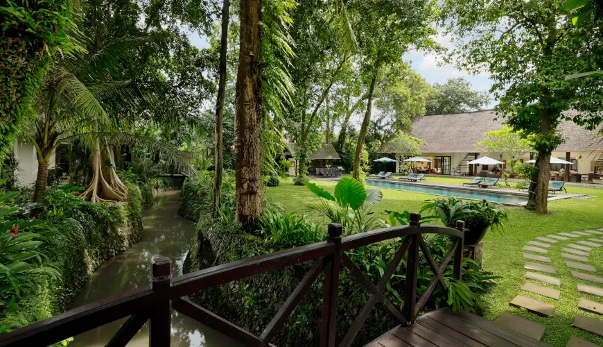 Lush garden with a small stream and footbridge at Villa Tirtadari