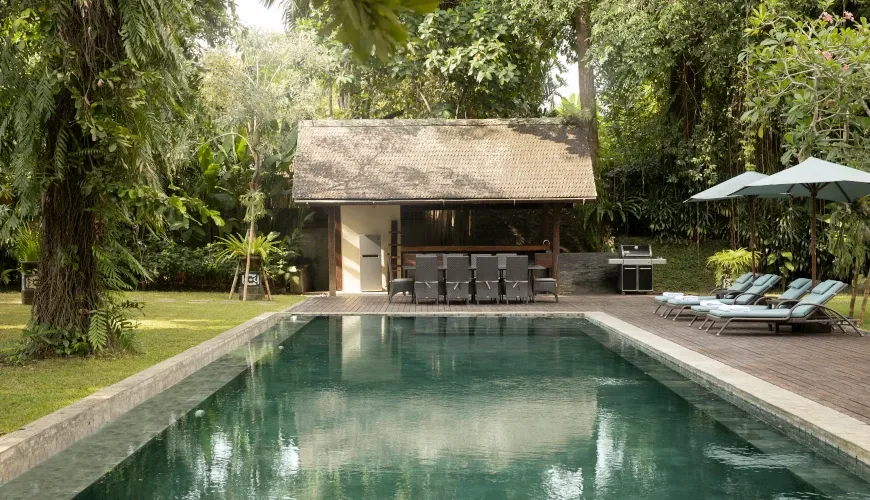 Luxury garden with a long narrow pool and lounge chairs at Villa Tirtadari