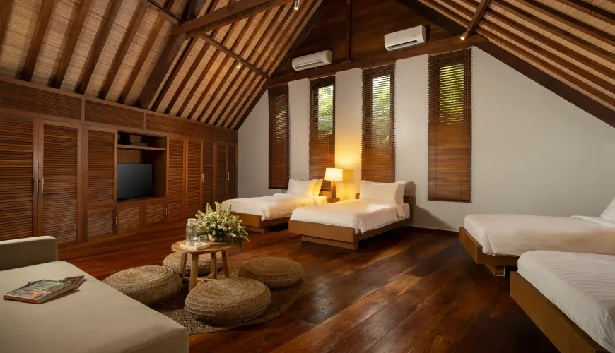 Spacious bedroom with three beds and a TV at Villa Tirtadari