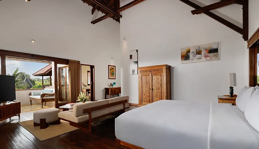 Airy and spacious villa bedroom featuring a large bed comfortable seating area and a private balcony at Villa Tropical Svasti