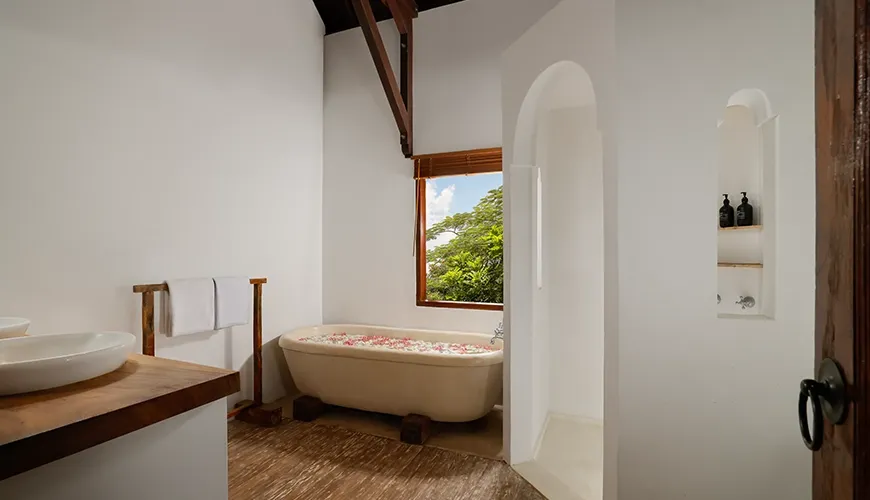 Beautiful villa bathroom featuring a deep soaking tub filled with flowers and rustic wood accents at Villa Tropical Svasti