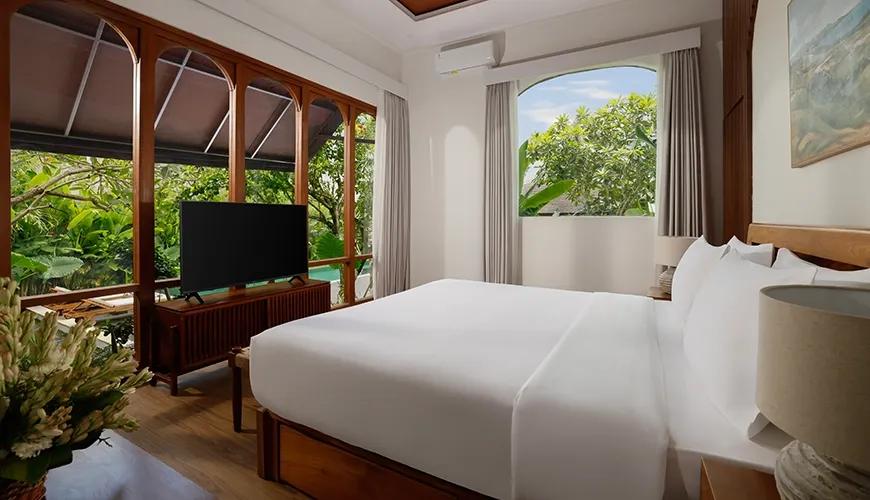 Elegant villa bedroom with a white king bed and large windows overlooking lush tropical garden greenery at Villa Tropical Svasti