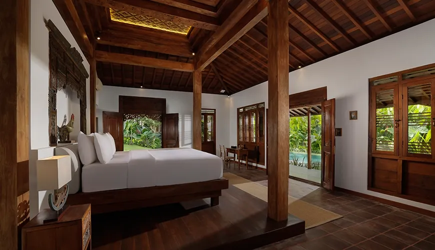 Luxurious joglo-style villa bedroom featuring rich dark wood floors and direct access to a private pool at Villa Tropical Svasti