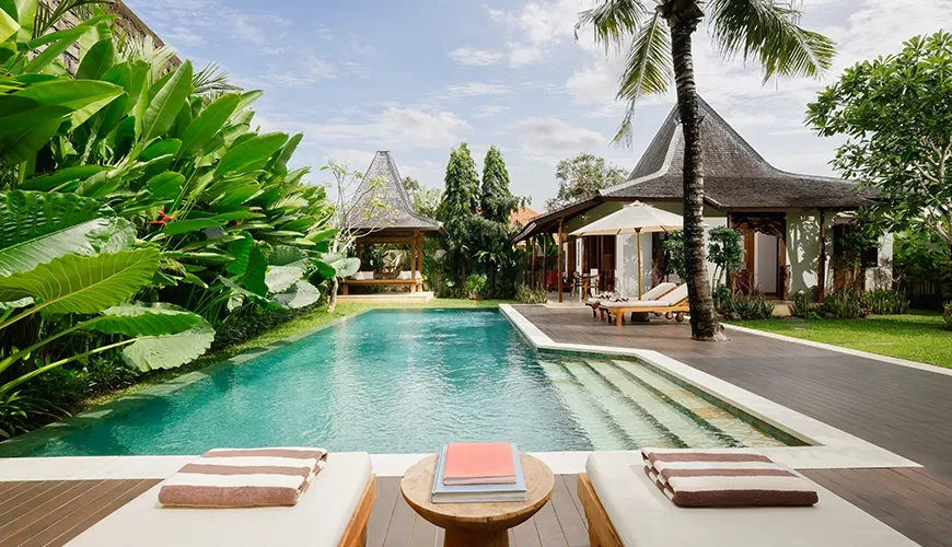Luxurious tropical villa pool area featuring comfortable sun loungers a beautiful wooden deck and lush green landscaping at Villa Tropical Svasti