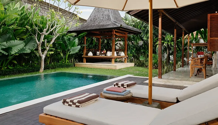 Luxury villa backyard featuring an inviting pool comfortable sun beds and a traditional covered lounge pavilion at Villa Tropical Svasti