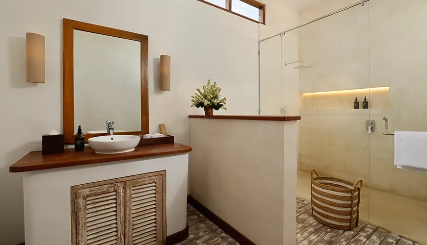 Modern villa bathroom featuring a bright vanity area glass walk-in shower and unique rustic wood flooring at Villa Tropical Svasti