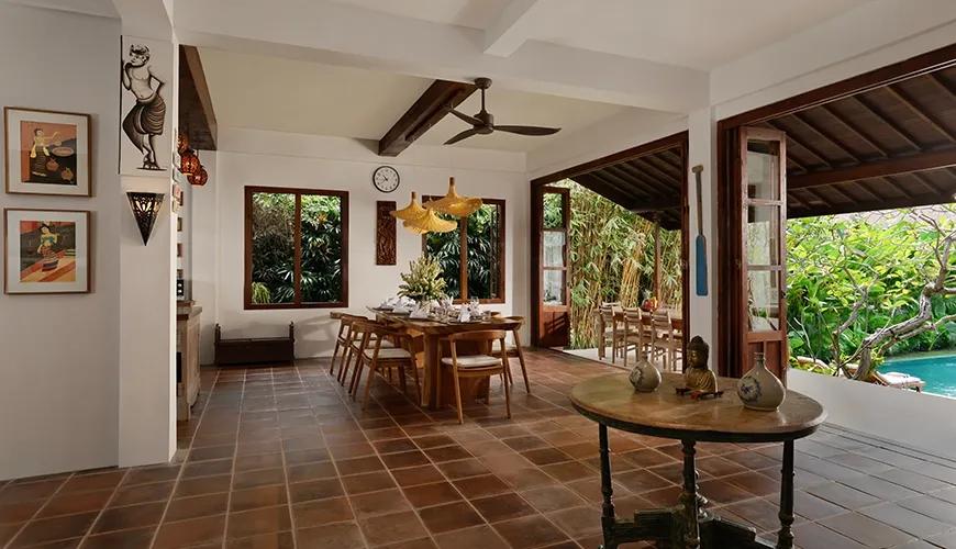 Open plan dining area of a luxury villa with a large table and poolside garden views at Villa Tropical Svasti