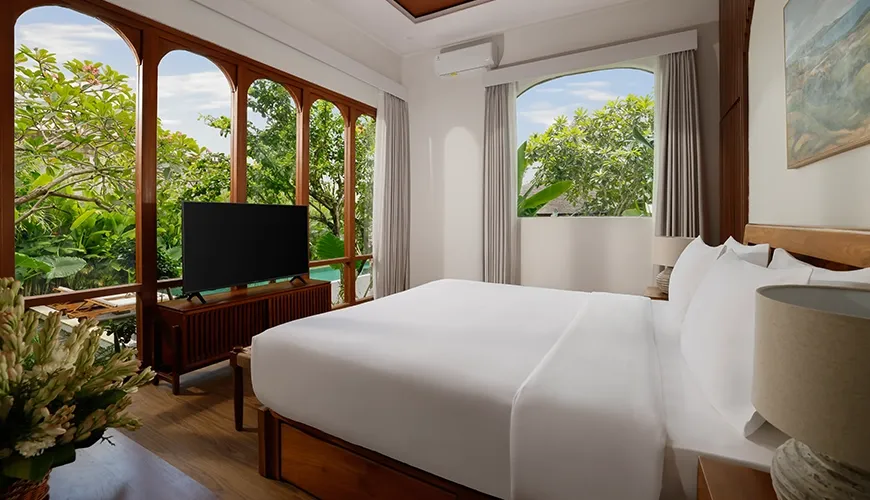 Stunning villa bedroom featuring a comfortable king-size bed massive arched windows and beautiful tropical garden views at Villa Tropical Svasti