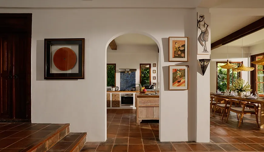 Welcoming villa entrance showcasing terracotta floor tiles traditional artwork and arched doorways leading to the kitchen at Villa Tropical Svasti