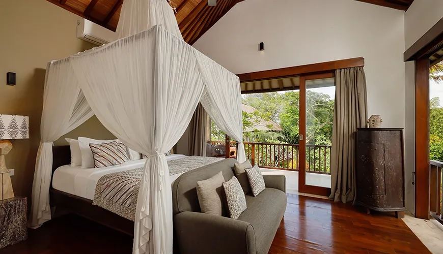 Cozy villa bedroom features a large wooden bed with white canopy and elegant pillows at Villa Uma Nina