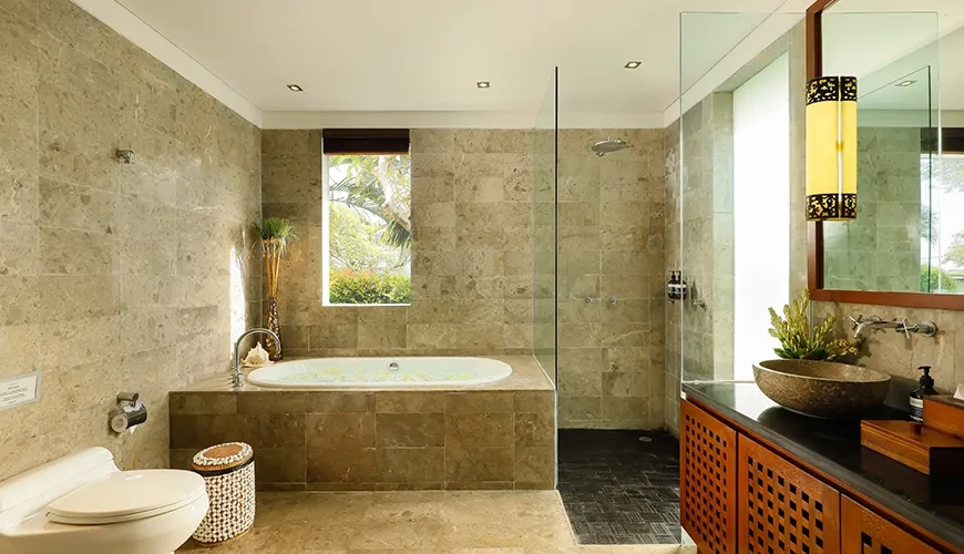 Luxurious stone bathroom featuring a beautiful built-in tub, wooden cabinets, and glass shower enclosure at Villa Uma Nina