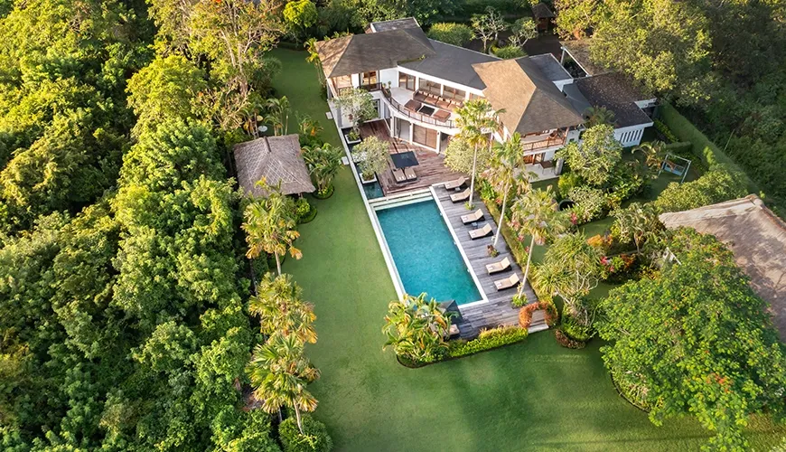 Magnificent aerial view of a large two story luxury villa with a long rectangular swimming pool and expansive green lawn at Villa Uma Nina
