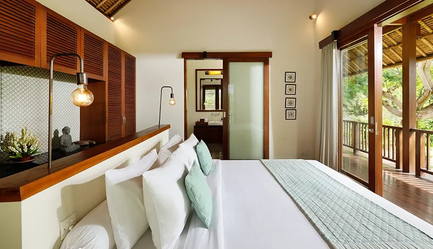 Serene villa bedroom featuring an elegant bed, large sliding glass doors, and a vaulted ceiling at Villa Uma Nina