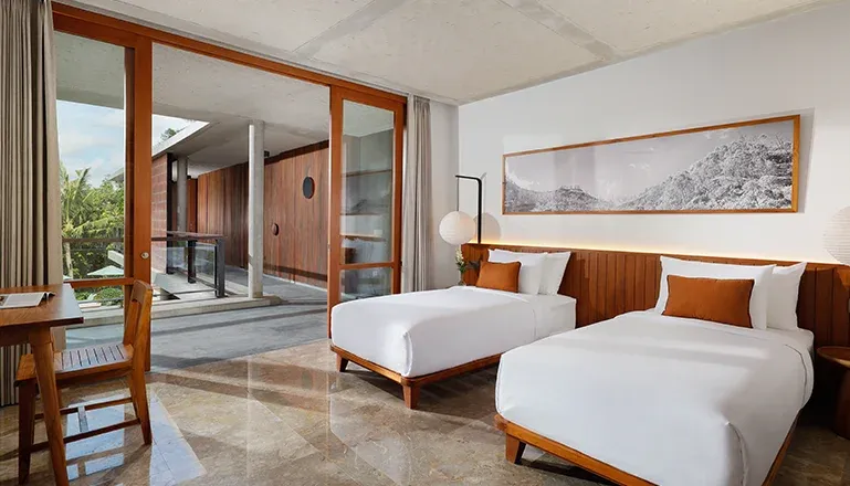 Well-lit bedroom with two comfortable single beds and artwork at Villa Uma Santai