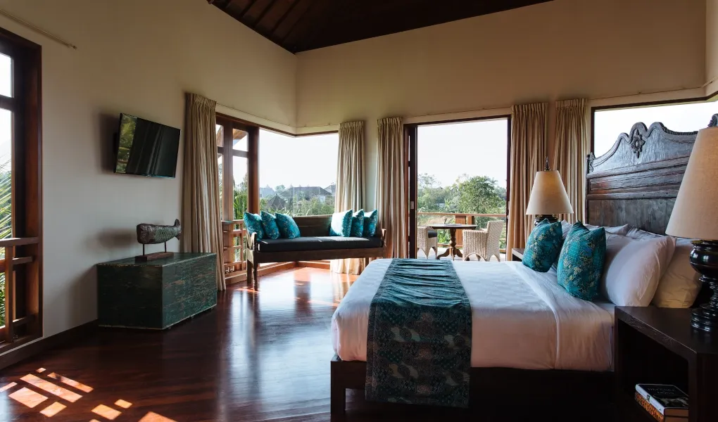Luxurious master suite with a canopy bed and balcony overlooking the garden at Villa Umah Daun