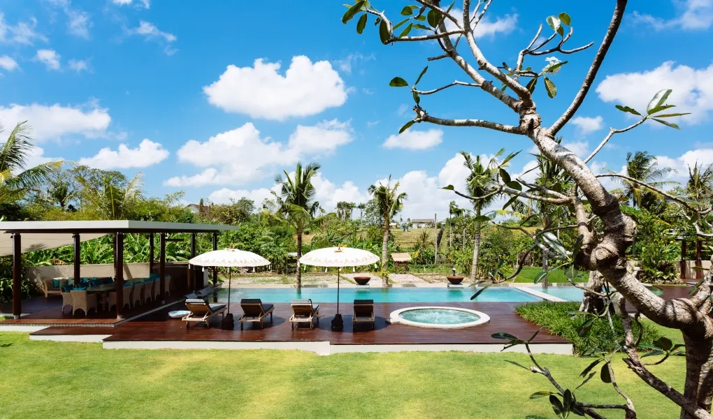Luxury villa pool with sun loungers and a lush green lawn at Villa Umah Daun