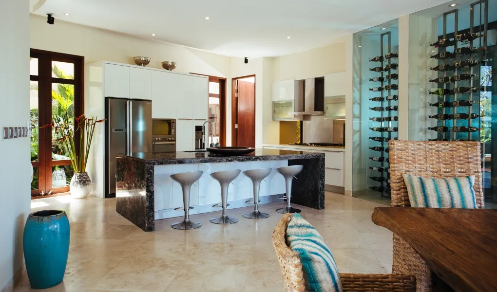 Modern kitchen with a marble island, bar stools, and a glass wine cellar at Villa Umah Daun