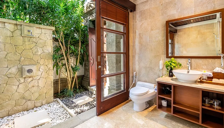 Beautiful villa bathroom with a sink, toilet, and an outdoor shower with tropical plants at Villa Umarya