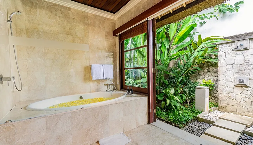 Serene villa bathroom with a large bathtub filled with flowers and a private outdoor garden at Villa Umarya