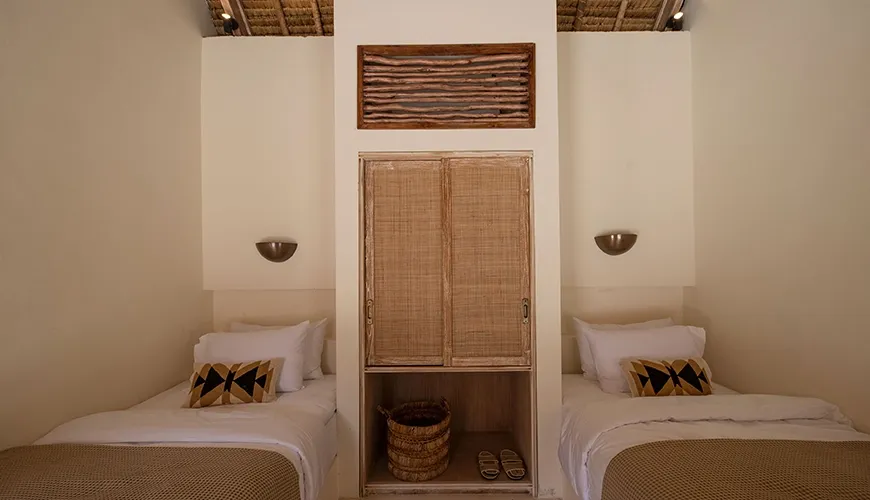 Charming twin bedroom inside the luxury villa featuring two single beds, a rattan cabinet, natural wood art, and a beautiful woven ceiling for guest comfort at Villa Xanadu