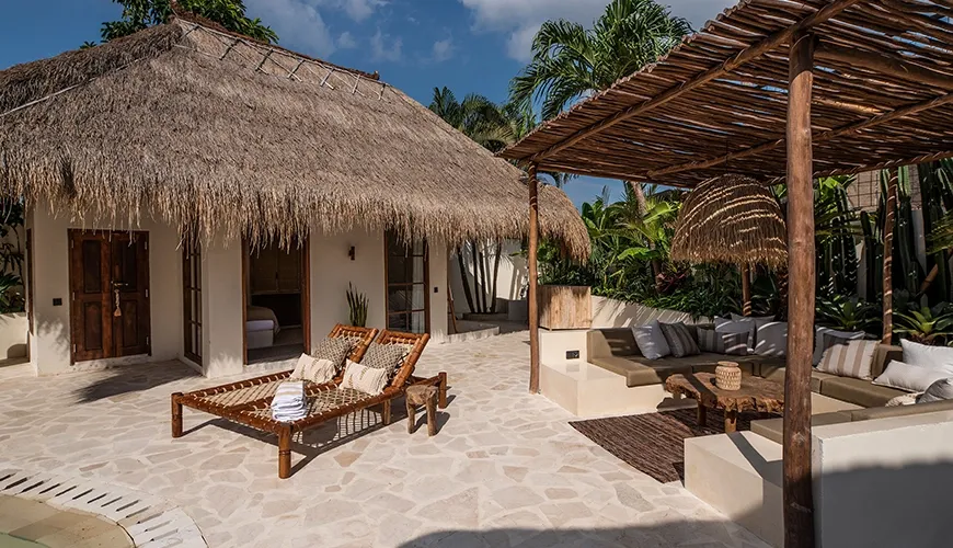 Exterior of a tropical villa with a thatched roof bungalow and an attractive shaded lounge area perfect for outdoor relaxation at Villa Xanadu