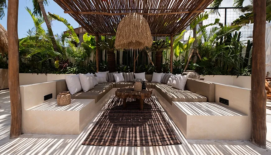 Inviting outdoor lounge area featuring built-in cushioned seating, large white pillows, and a beautiful natural rattan shade roof for enjoying the tropical sun at Villa Xanadu