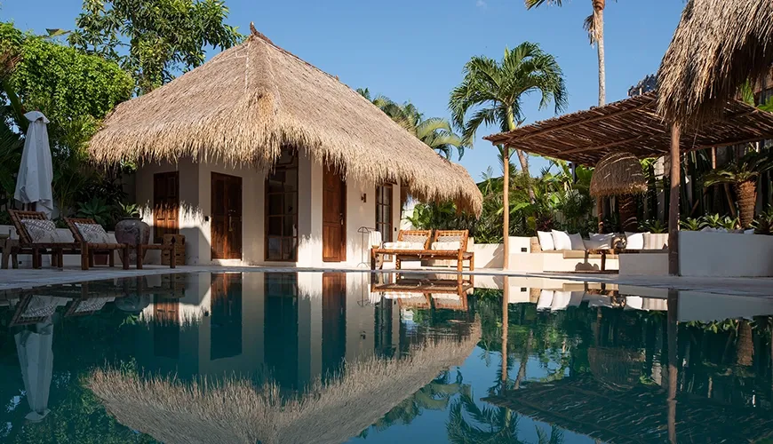 Luxurious private villa swimming pool reflecting the gorgeous traditional thatched roof bungalow and tropical lush gardens at Villa Xanadu
