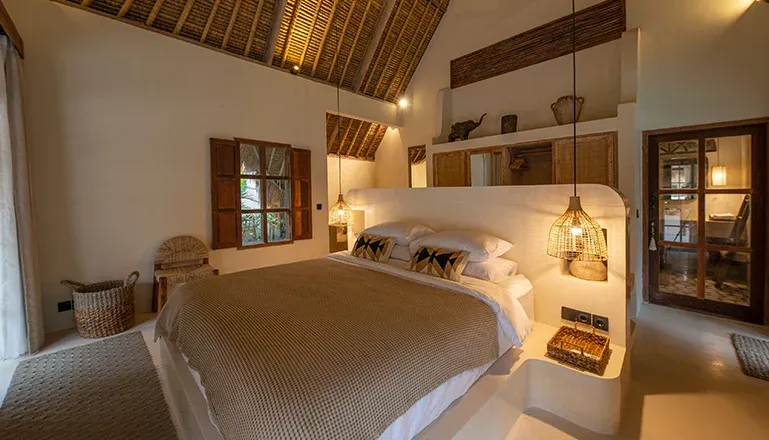 Serene bedroom with a cozy bed and a thatched ceiling at Villa Xanadu