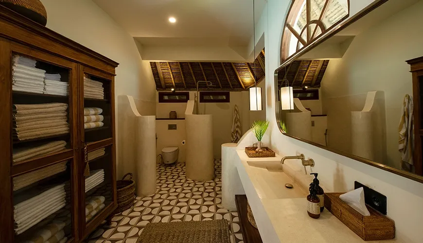 Spacious luxury villa bathroom showcasing a large custom stone vanity, antique wooden linen cabinet, and a traditional thatched ceiling for a relaxing experience at Villa Xanadu