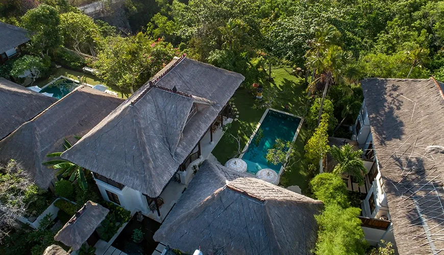 Aerial drone view showcasing multiple private villas with swimming pools surrounded by a thick, lush tropical forest at VillaYasmine