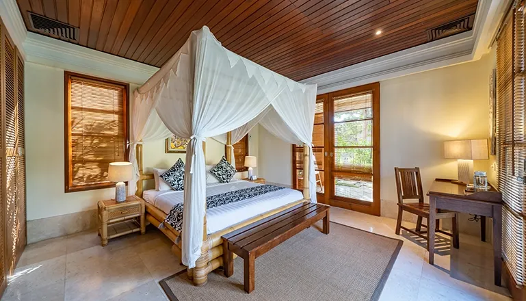 Bright bedroom features four-poster bed opening to lush tropical views at Villa Yasmine