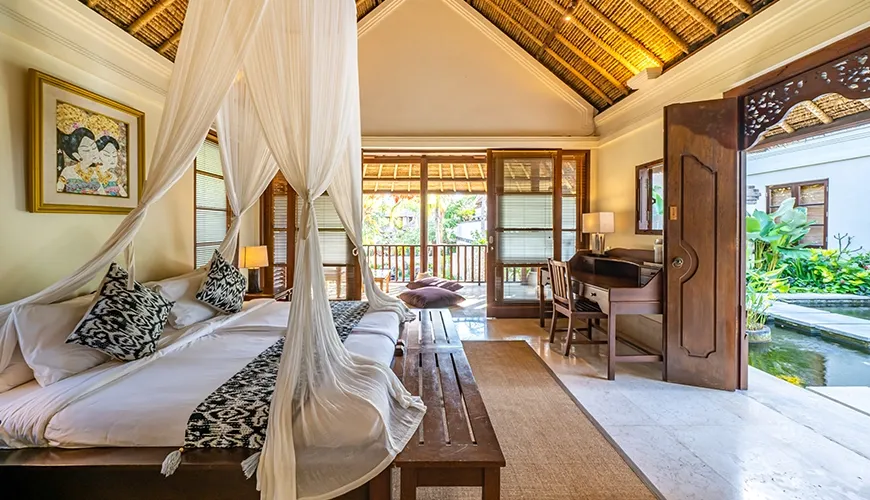 Elegant villa bedroom featuring a beautiful canopy bed, traditional thatched roof, and a private balcony at Villa Yasmine