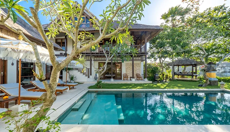 Elegant private villa with a sparkling swimming pool surrounded by lush green grass and sun loungers at Villa Yasmine