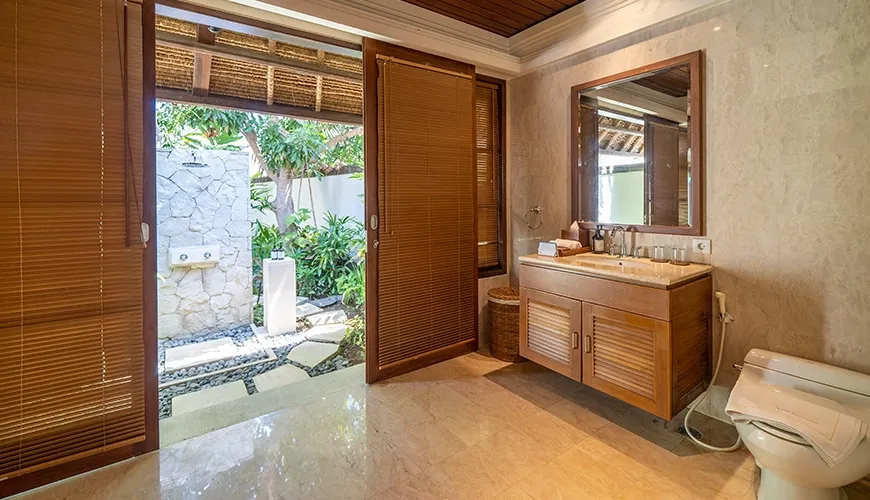 Luxurious bathroom with an elegant wooden vanity and a large glass door that opens to a beautiful outdoor shower at Villa Yasmine