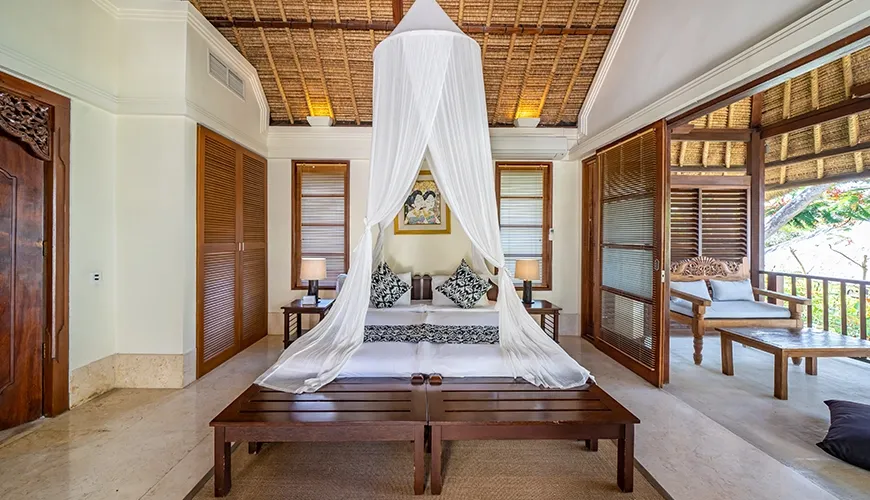Luxurious bedroom with canopy bed and private outdoor seating area at Villa Yasmine